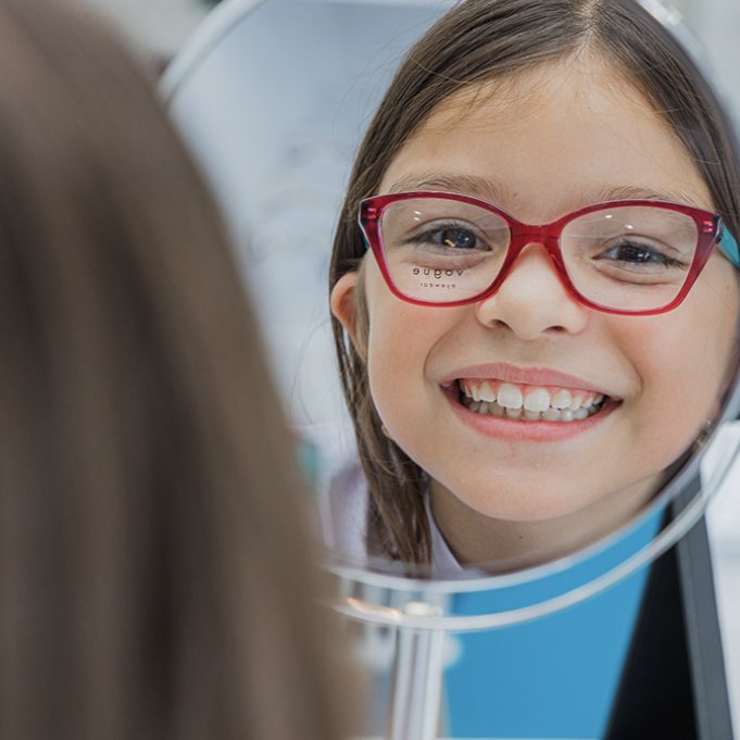 Girl smiling in red frames in the mirror