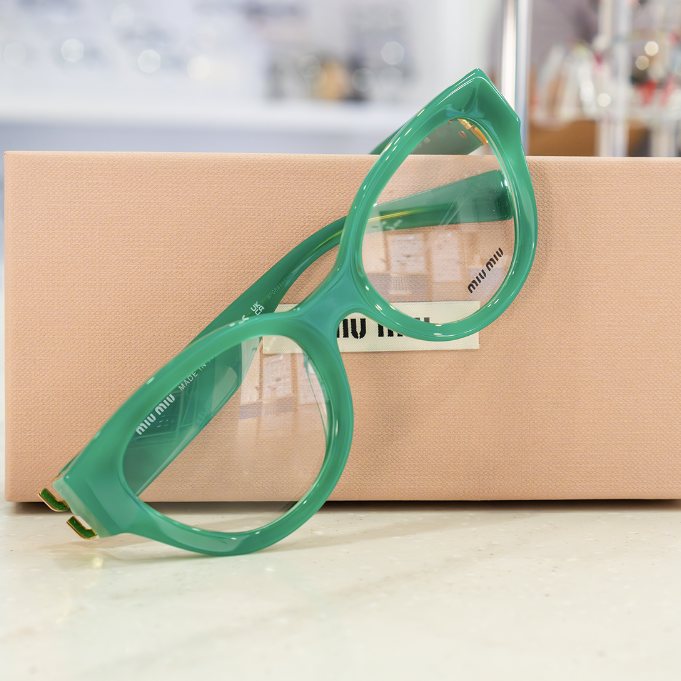 Green cat-eye frames on a pink box