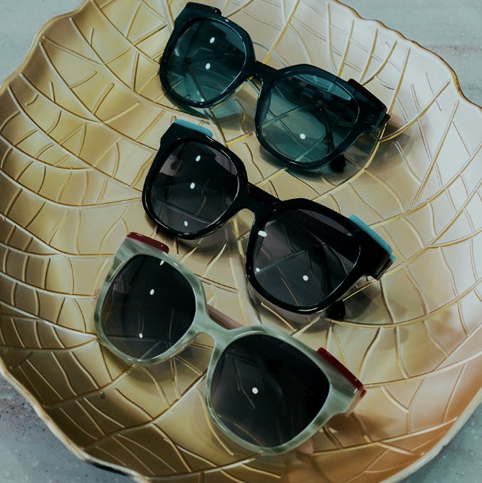 Three pairs of sunglasses on a gold leaf tray