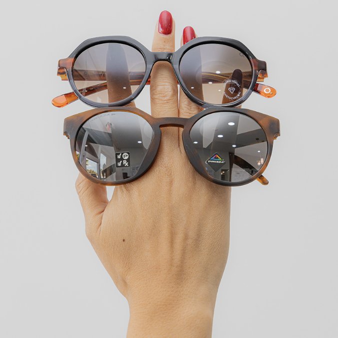 Two pairs of round sunglasses held up on fingers